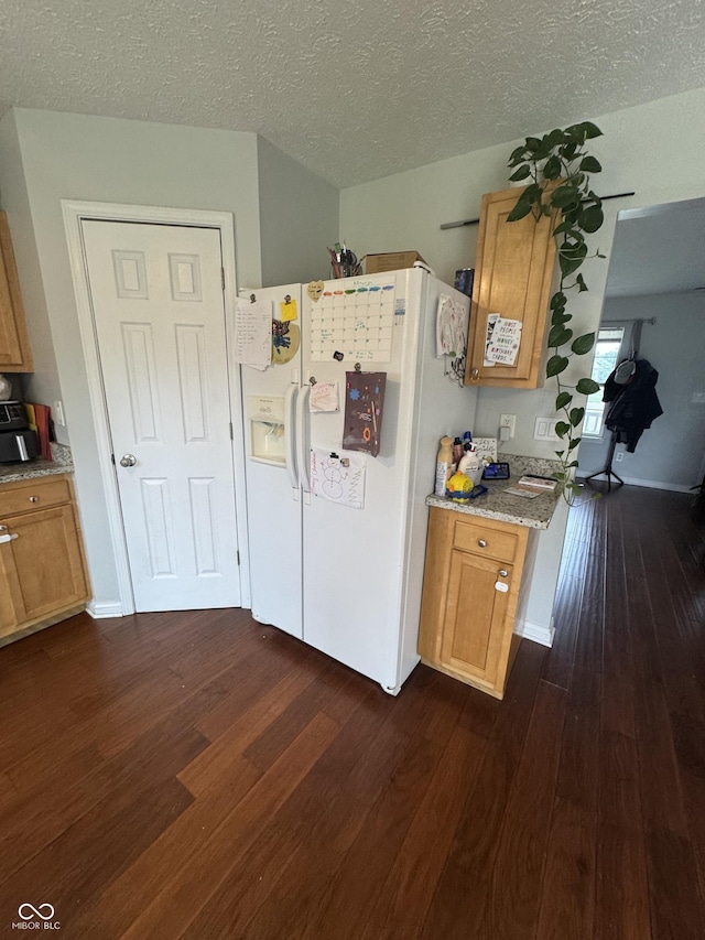 6027 Moonseed Cir, Indianapolis, IN 46203 - kitchen featuring white fridge with ice dispenser, dark wood-style floors, light stone counters, a textured ceiling, and brown cabinets