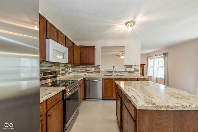14523 Lee Stewart Ln, Fishers, IN 46038 - kitchen featuring stainless steel appliances, backsplash, a ceiling fan, light stone counters, and a center island