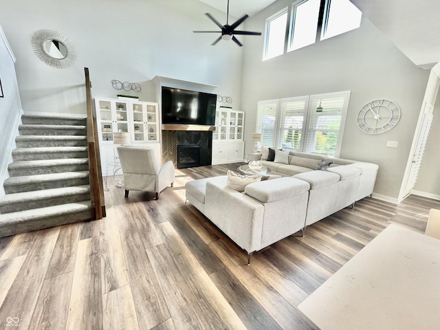 4281 Viewforth Ln, Bargersville, IN 46106 - living area with ceiling fan, a glass covered fireplace, wood finished floors, stairs, and a high ceiling