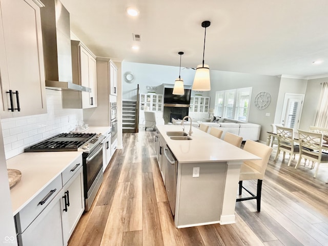 4281 Viewforth Ln, Bargersville, IN 46106 - kitchen featuring appliances with stainless steel finishes, wall chimney range hood, a kitchen bar, a kitchen island with sink, and light wood-style flooring