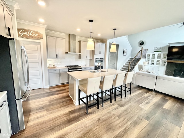 4281 Viewforth Ln, Bargersville, IN 46106 - kitchen with stainless steel appliances, wall chimney exhaust hood, a kitchen bar, open floor plan, and light wood-type flooring