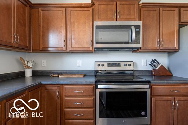 12584 Cold Stream Rd, Noblesville, IN 46060 - kitchen with stainless steel appliances, dark countertops, and brown cabinets