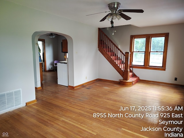 8955 N County Road 925 E, Seymour, IN 47274 - unfurnished living room featuring a ceiling fan, wood finished floors, arched walkways, and stairs
