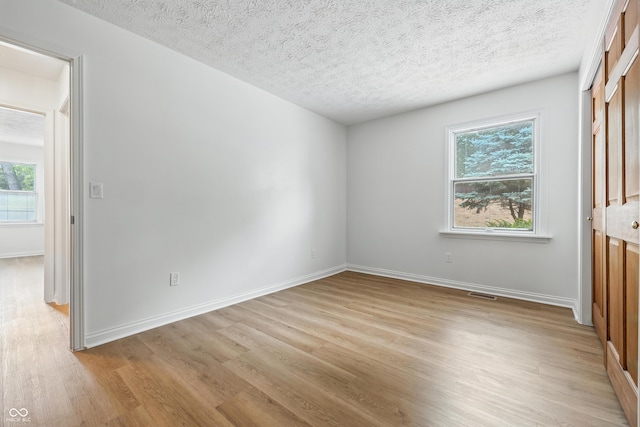 5982 Oak Hill E Dr, Plainfield, IN 46168 - unfurnished bedroom with light wood finished floors, multiple windows, and a textured ceiling