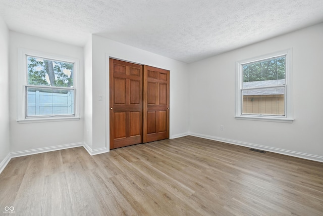 5982 Oak Hill E Dr, Plainfield, IN 46168 - unfurnished bedroom with light wood-type flooring, a textured ceiling, multiple windows, and a closet
