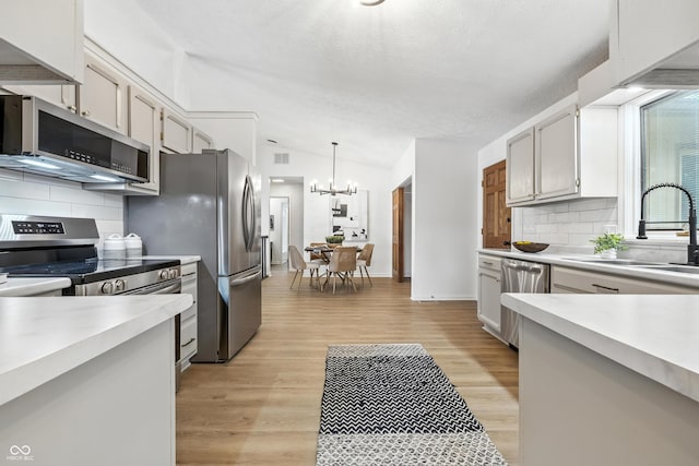 5982 Oak Hill E Dr, Plainfield, IN 46168 - kitchen with appliances with stainless steel finishes, light countertops, a chandelier, backsplash, and vaulted ceiling