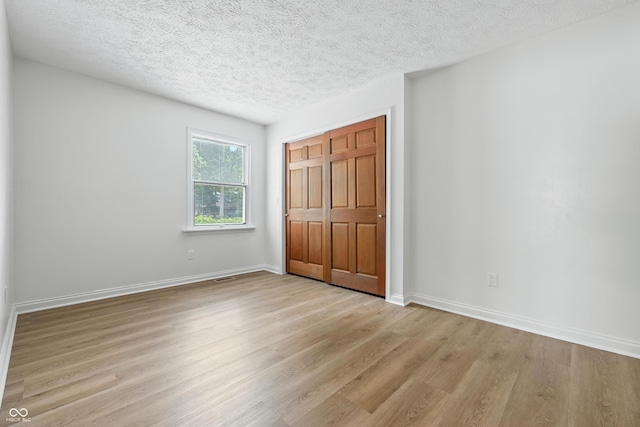 5982 Oak Hill E Dr, Plainfield, IN 46168 - unfurnished bedroom with light wood-style flooring, a textured ceiling, and a closet