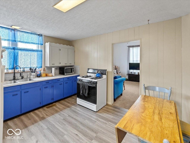 215 N E St, Greensburg, IN 47240 - kitchen featuring stainless steel microwave, white range with gas cooktop, blue cabinetry, a textured ceiling, and light countertops