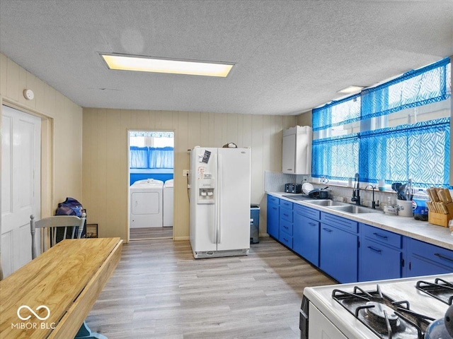 215 N E St, Greensburg, IN 47240 - kitchen featuring white refrigerator with ice dispenser, separate washer and dryer, blue cabinetry, light wood-style flooring, and light countertops