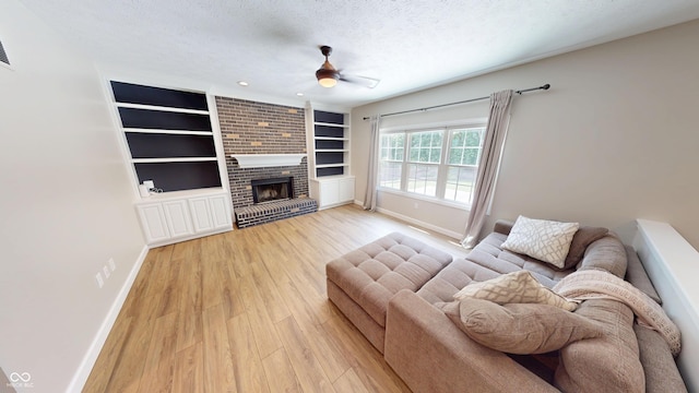 9831 Deering St, Fishers, IN 46037 - living area with a textured ceiling, light wood-type flooring, ceiling fan, built in shelves, and a brick fireplace