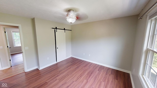9831 Deering St, Fishers, IN 46037 - unfurnished bedroom featuring a barn door, wood finished floors, and ceiling fan