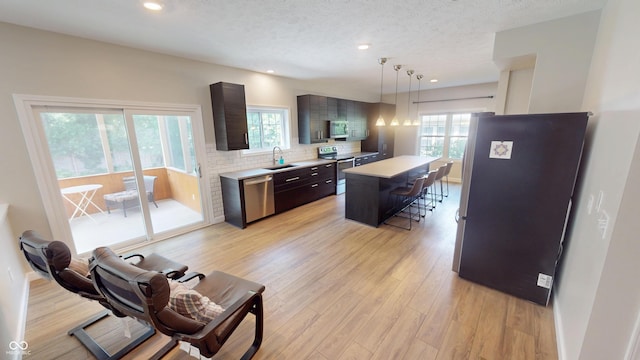 9831 Deering St, Fishers, IN 46037 - kitchen with appliances with stainless steel finishes, light countertops, a breakfast bar area, tasteful backsplash, and a textured ceiling
