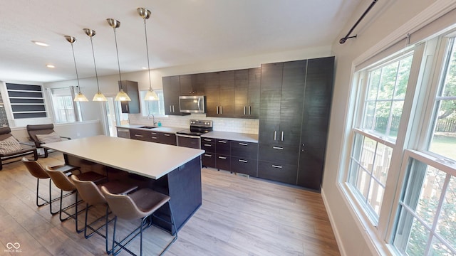 9831 Deering St, Fishers, IN 46037 - kitchen featuring appliances with stainless steel finishes, a kitchen bar, light wood-type flooring, healthy amount of natural light, and recessed lighting