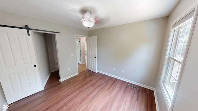 9831 Deering St, Fishers, IN 46037 - unfurnished bedroom with wood finished floors, a barn door, and ceiling fan