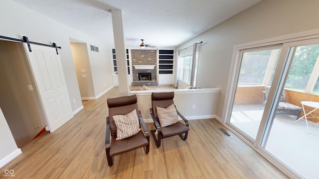 9831 Deering St, Fishers, IN 46037 - dining room featuring ceiling fan, a brick fireplace, light wood-style floors, a barn door, and built in shelves