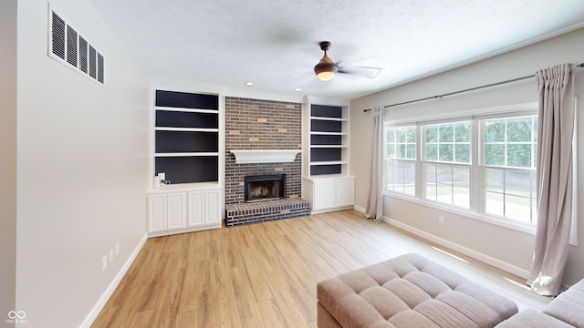 9831 Deering St, Fishers, IN 46037 - living area with a textured ceiling, light wood finished floors, ceiling fan, built in shelves, and a brick fireplace