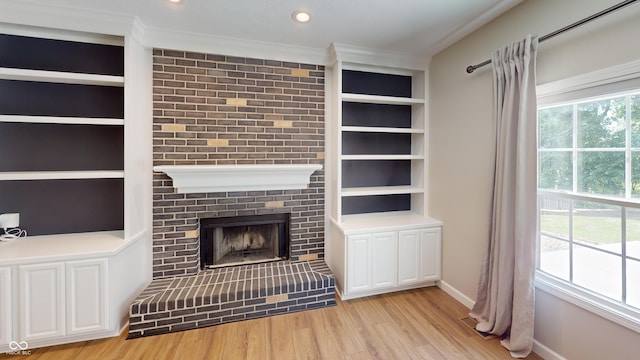 9831 Deering St, Fishers, IN 46037 - unfurnished living room featuring a brick fireplace, wood finished floors, ornamental molding, built in shelves, and recessed lighting