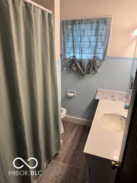 2830 Guilford Ave, Indianapolis, IN 46205 - full bathroom featuring tile walls, vanity, wood finished floors, a wainscoted wall, and a shower with shower curtain