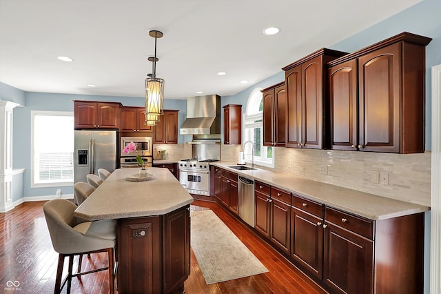10587 Proposal Pointe Way, Fishers, IN 46040 - kitchen featuring wall chimney exhaust hood, stainless steel appliances, dark wood finished floors, a kitchen island, and recessed lighting