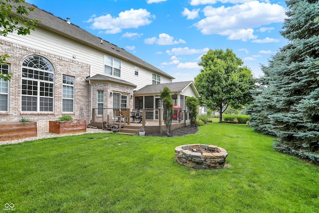 10587 Proposal Pointe Way, Fishers, IN 46040 - back of house with a fire pit, a deck, a yard, a sunroom, and brick siding