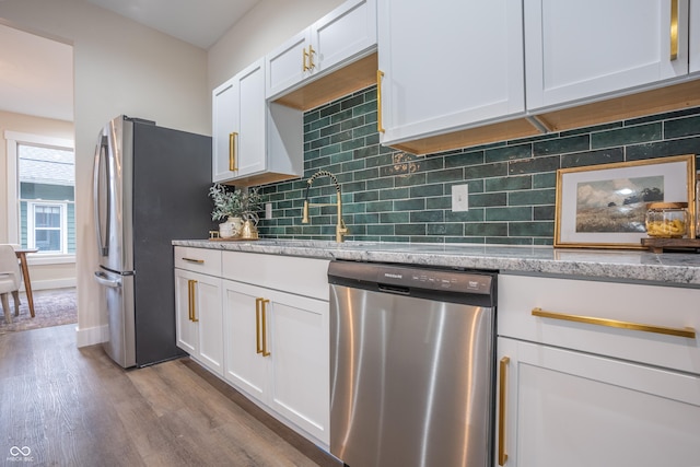 5511 E University Ave, Indianapolis, IN 46219 - kitchen featuring stainless steel appliances, wood finished floors, white cabinetry, and decorative backsplash