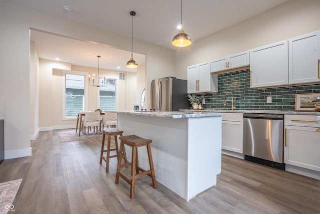 5511 E University Ave, Indianapolis, IN 46219 - kitchen with appliances with stainless steel finishes, decorative backsplash, wood finished floors, a kitchen island, and a chandelier