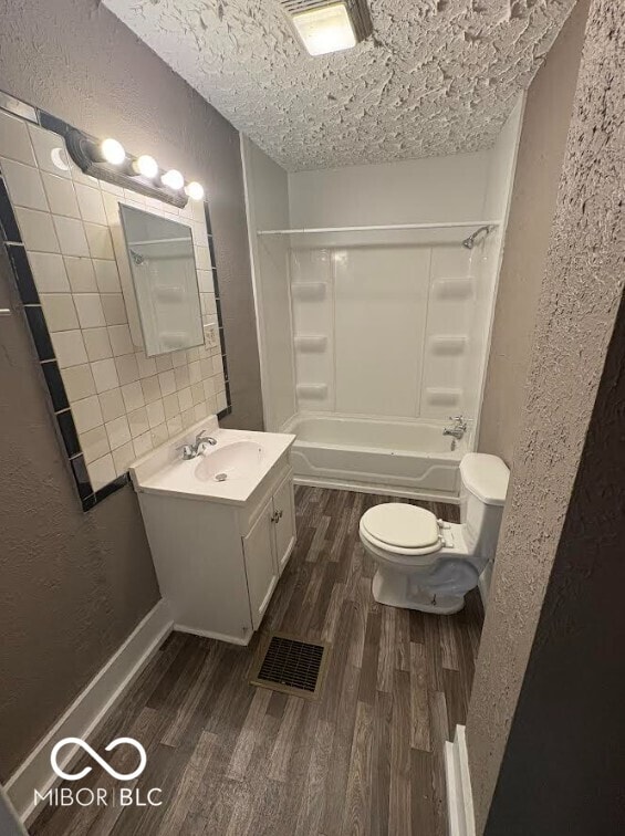 1521 N Tacoma Ave, Indianapolis, IN 46201 - bathroom with wood finished floors, a textured wall, vanity, shower / washtub combination, and a textured ceiling