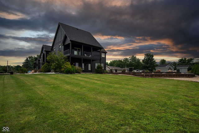 3306 Mullinix Rd, Greenwood, IN 46143 - back of property at dusk with a balcony, a yard, and roof with shingles