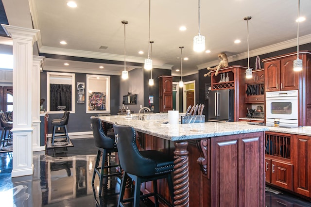3306 Mullinix Rd, Greenwood, IN 46143 - kitchen featuring high quality fridge, decorative columns, crown molding, a large island with sink, and a kitchen bar