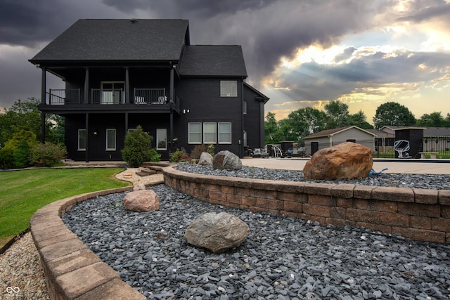 3306 Mullinix Rd, Greenwood, IN 46143 - back of property at dusk featuring a balcony, a lawn, and a patio