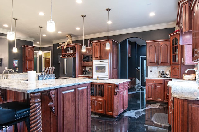 3306 Mullinix Rd, Greenwood, IN 46143 - kitchen featuring high quality fridge, white oven, a kitchen island, arched walkways, and ornamental molding