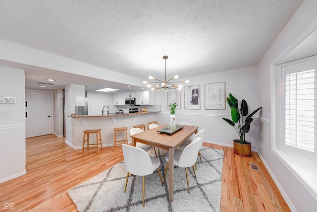 8178 Foxchase Cir, Indianapolis, IN 46256 - dining space with a chandelier, a textured ceiling, and light wood-type flooring