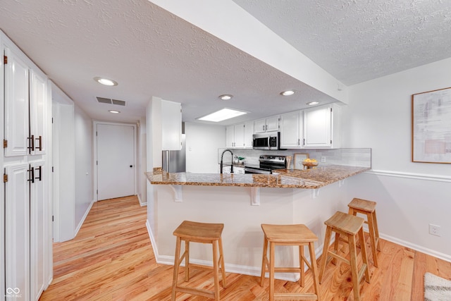 8178 Foxchase Cir, Indianapolis, IN 46256 - kitchen featuring stainless steel appliances, a textured ceiling, light wood-style flooring, light stone counters, and white cabinetry