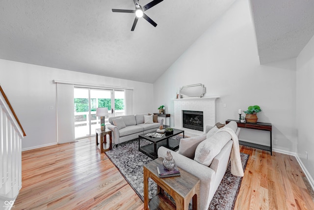8178 Foxchase Cir, Indianapolis, IN 46256 - living area with ceiling fan, vaulted ceiling, light wood-style flooring, a fireplace, and a textured ceiling