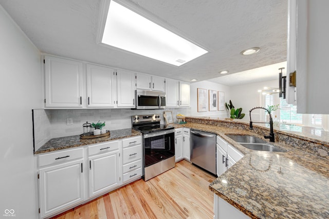 8178 Foxchase Cir, Indianapolis, IN 46256 - kitchen with stainless steel appliances, dark stone counters, light wood-type flooring, white cabinets, and recessed lighting