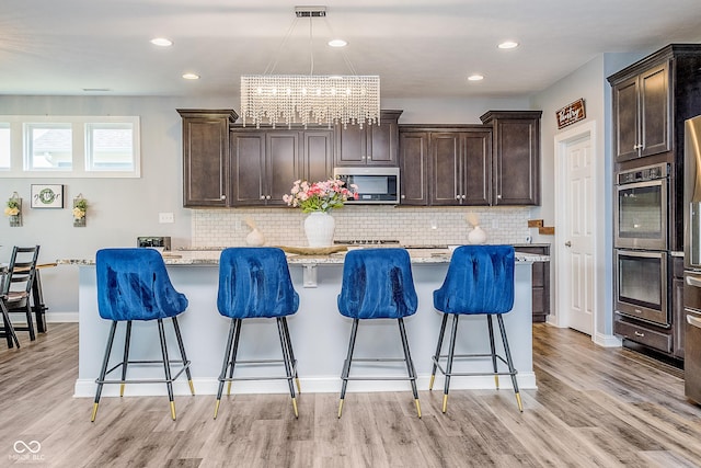 12634 Mustard Seed Ct, Fishers, IN 46038 - kitchen with stainless steel appliances, dark brown cabinetry, a breakfast bar area, and recessed lighting