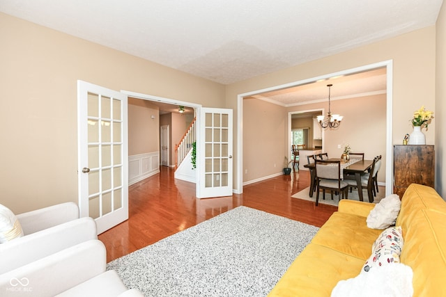 13700 Stanford Dr, Carmel, IN 46074 - living room featuring wood finished floors, stairs, a chandelier, ornamental molding, and french doors
