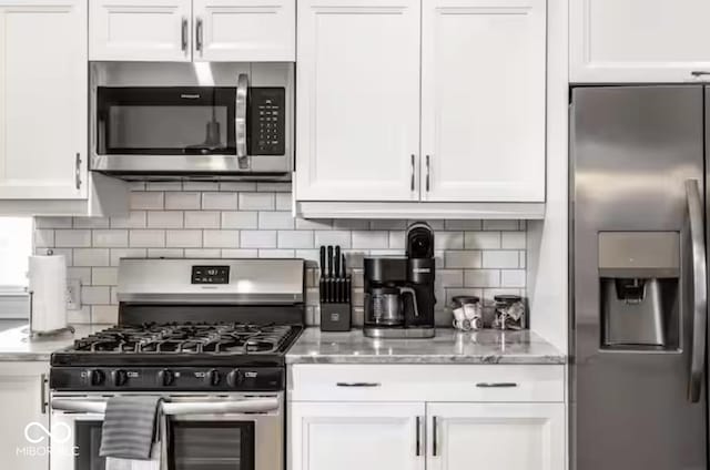 213 E 15th St, Indianapolis, IN 46202 - kitchen with appliances with stainless steel finishes, white cabinetry, light stone counters, and tasteful backsplash