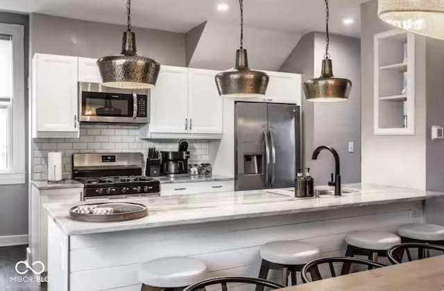 213 E 15th St, Indianapolis, IN 46202 - kitchen with stainless steel appliances, light stone countertops, backsplash, white cabinetry, and vaulted ceiling