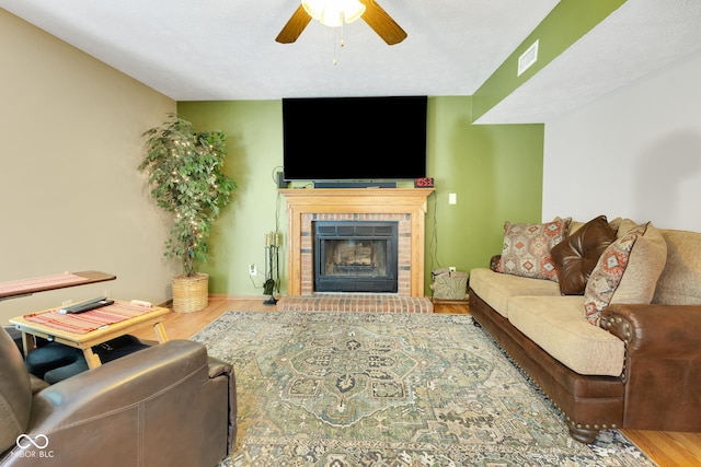 6439 Bower Dr, Indianapolis, IN 46241 - living room featuring a ceiling fan, a tiled fireplace, and wood finished floors