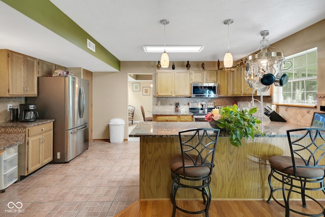 6439 Bower Dr, Indianapolis, IN 46241 - kitchen featuring appliances with stainless steel finishes, a peninsula, backsplash, a kitchen bar, and decorative light fixtures