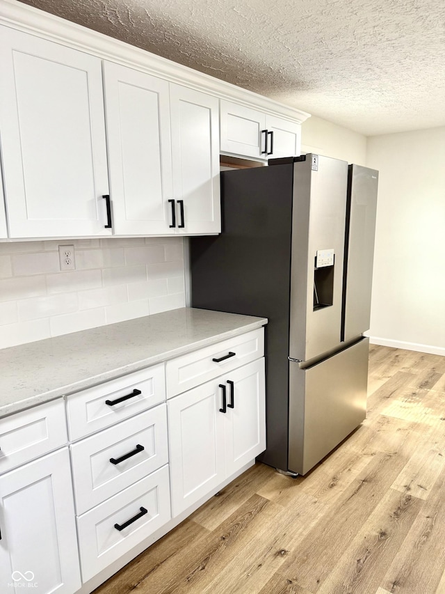 405 E Cowing Dr, Muncie, IN 47303 - kitchen featuring light wood-type flooring, backsplash, a textured ceiling, white cabinetry, and stainless steel fridge