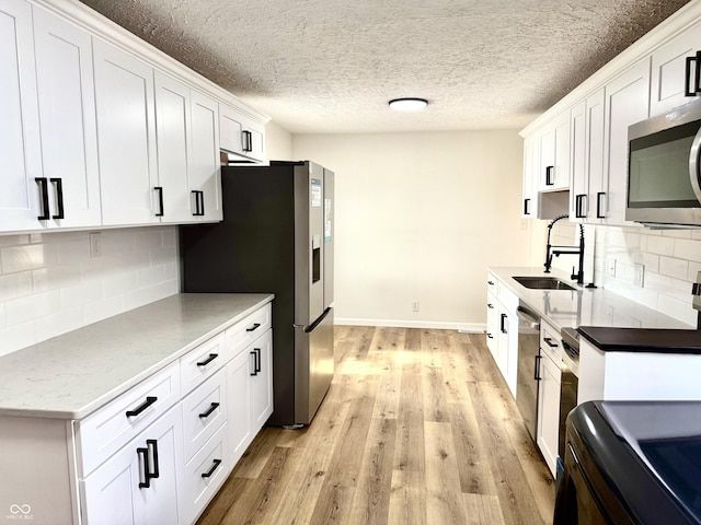 405 E Cowing Dr, Muncie, IN 47303 - kitchen featuring appliances with stainless steel finishes, white cabinetry, tasteful backsplash, light wood-type flooring, and a textured ceiling