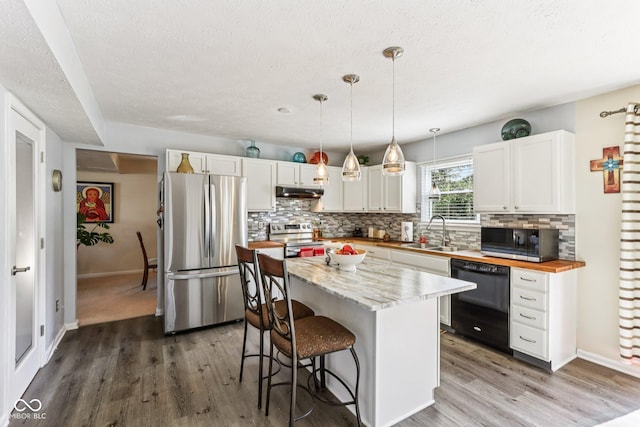 6711 Crestwell Ln, Indianapolis, IN 46268 - kitchen with appliances with stainless steel finishes, under cabinet range hood, tasteful backsplash, wood finished floors, and a textured ceiling