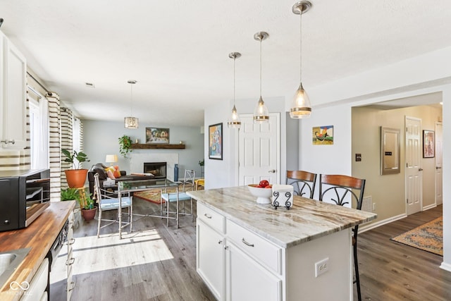 6711 Crestwell Ln, Indianapolis, IN 46268 - kitchen featuring dark wood-style flooring, a fireplace, white cabinetry, and a kitchen breakfast bar