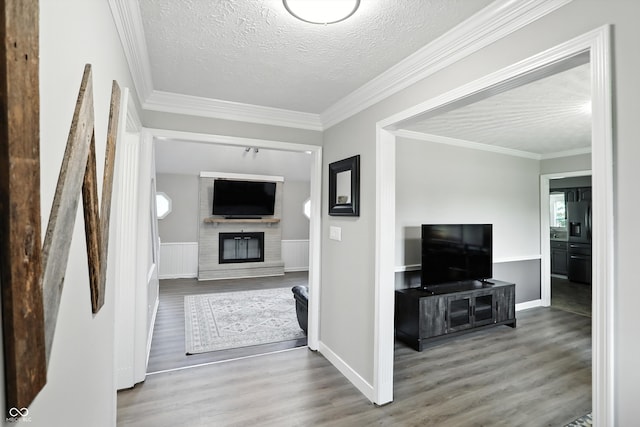 8030 5 Points Rd, Indianapolis, IN 46259 - unfurnished living room with wood finished floors, a brick fireplace, a textured ceiling, a wainscoted wall, and crown molding