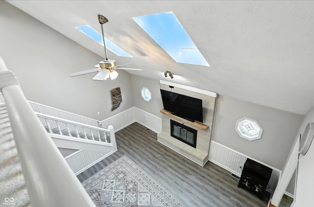 8030 5 Points Rd, Indianapolis, IN 46259 - unfurnished living room with a skylight, vaulted ceiling, wood finished floors, a glass covered fireplace, and a ceiling fan