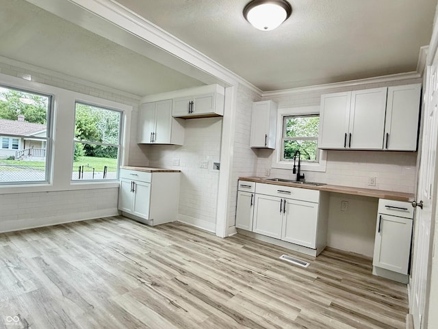 3712 S Kealing Ave S, Indianapolis, IN 46237 - kitchen featuring wood counters, light wood-style flooring, crown molding, white cabinets, and decorative backsplash