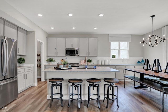 5343 Pelion Pl, Mccordsville, IN 46055 - kitchen with appliances with stainless steel finishes, backsplash, a kitchen bar, light wood-type flooring, and recessed lighting
