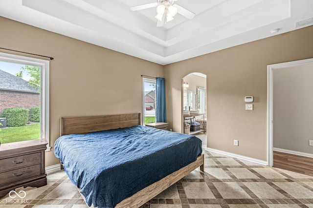 2920 Bloomsbury S, Greenwood, IN 46143 - bedroom featuring a tray ceiling, arched walkways, connected bathroom, and ceiling fan